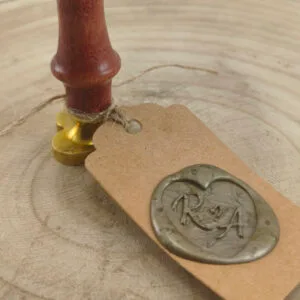 Close up of Wooden Stamp with Gold Base Resting on Kraft Tag Tied with Twine on Wooden Surface